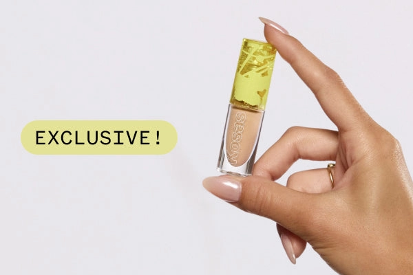 A hand holding a concealer tube next to an Exclusive sticker